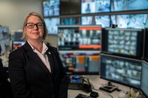 Woman standing with security system monitors in the background