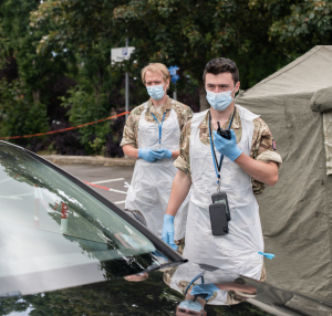 Pair of military members approaching a car wearing sanitary protective articles