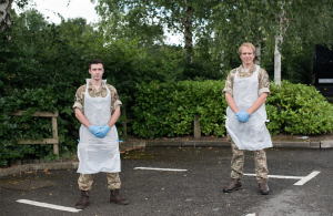 Two soldiers wearing protective equipment in a parking lot