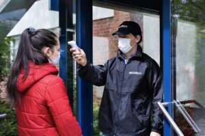 Security taking temperature of a visitor