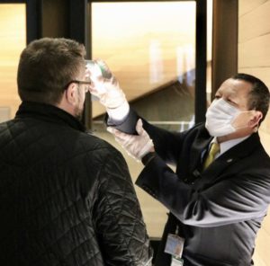 Security guard scanning guest's forehead for his temperature