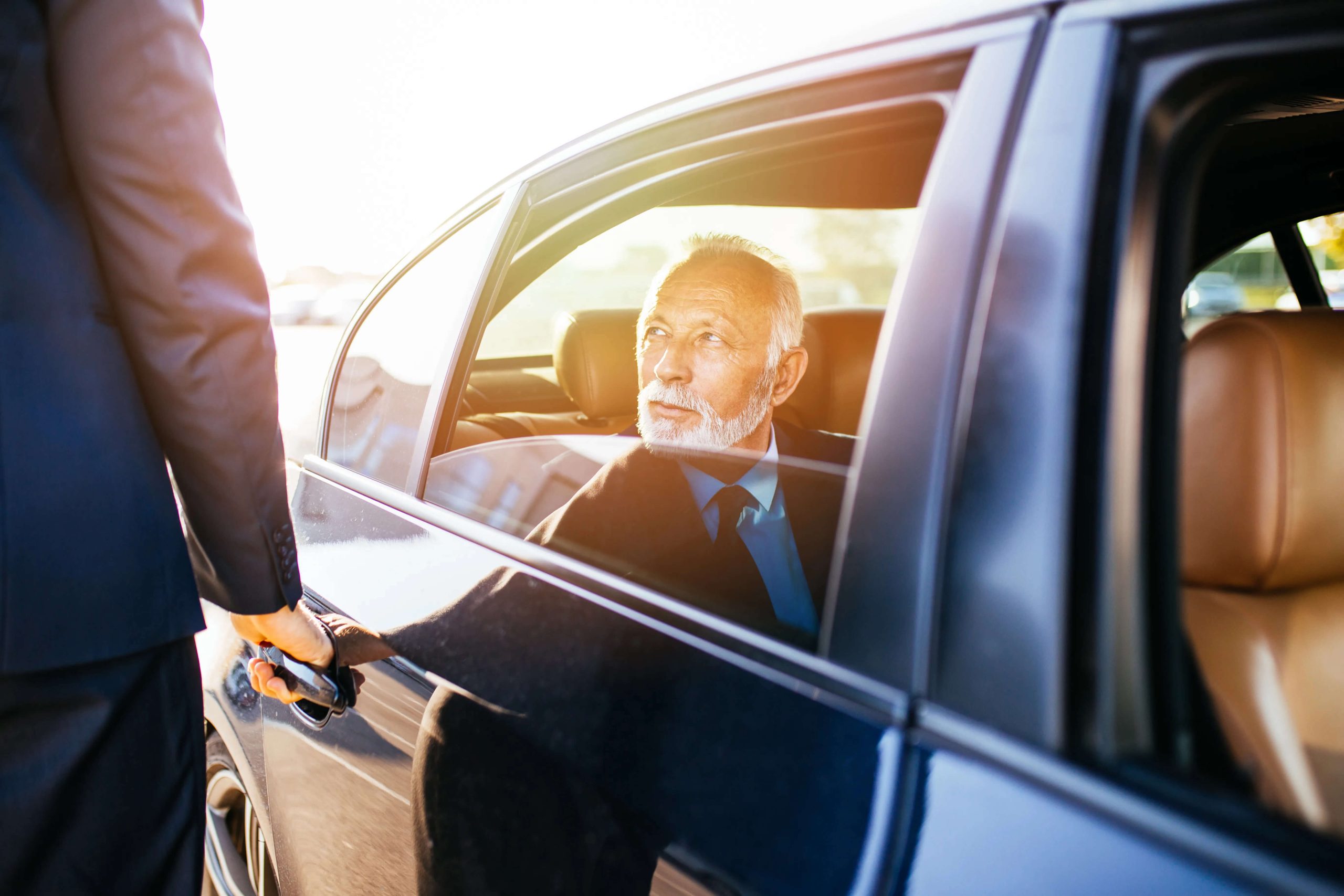 Old business man looks at another man while in a car