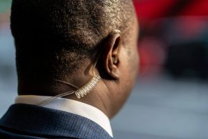 View of a security guard's head from the back; he is wearing an earpiece.